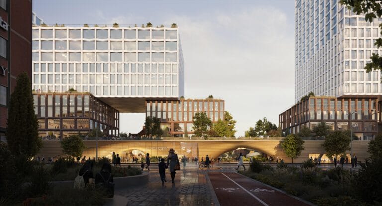 Public plaza between modern glass and grid buildings with a raised walkway and people walking or cycling beneath a clear sky