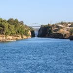 Wide river between forested cliffs an arched green bridge spans the gorge in the distance