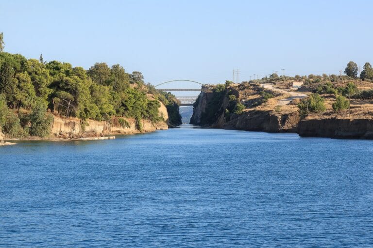 Wide river between forested cliffs an arched green bridge spans the gorge in the distance
