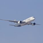 Airbus A350 XWB aircraft in flight against a clear blue sky with two large engines and swept wings visible