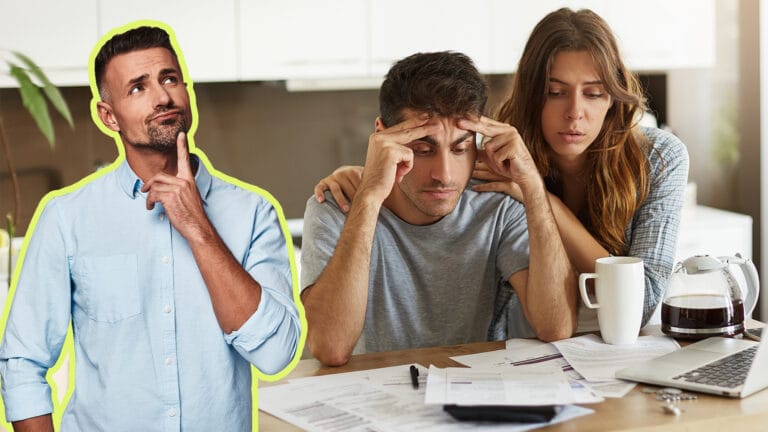 Man in a blue shirt stands apart finger on chin while a couple looks stressed over papers at a table