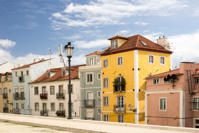 Colorful row of pastel houses with red tile roofs under a bright blue sky a vintage street lamp in the foreground