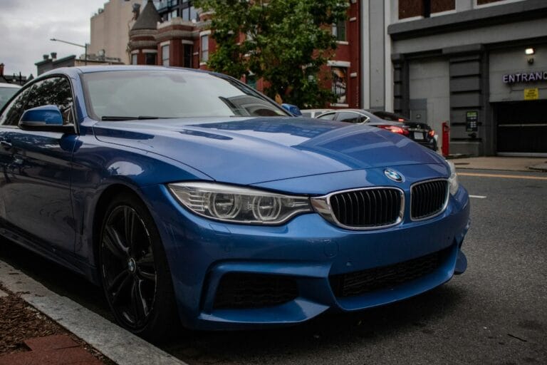 Blue BMW sedan parked along a city street with brick buildings in the background front left view