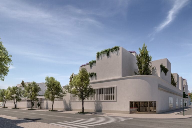 White modern building with rooftop greenery trees along the sidewalk and a crosswalk under a clear blue sky