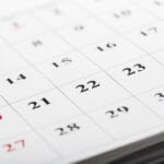 Close up of a calendar page showing a grid of dates with Sundays in red and weekdays in black