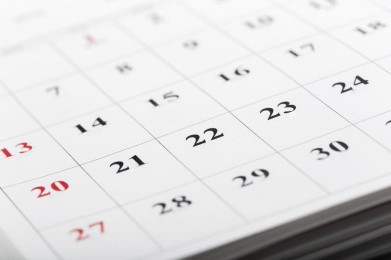 Close up of a calendar page showing a grid of dates with Sundays in red and weekdays in black