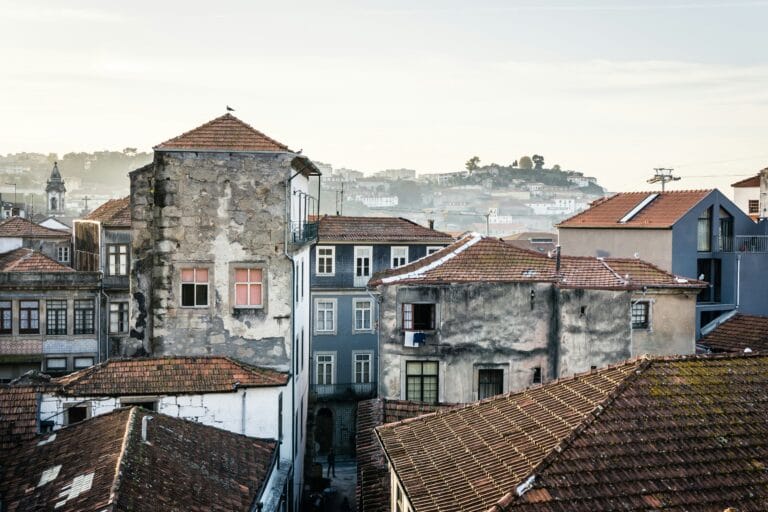 Aerial view of a European town with red tiled roofs narrow streets and a distant hillside town in soft light