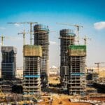 Under construction high rise buildings with yellow tower cranes against a clear blue sky