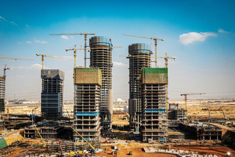 Under construction high rise buildings with yellow tower cranes against a clear blue sky