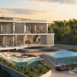 Modern glass walled villa with terraces outdoor seating and an infinity pool at sunset by lush landscaping