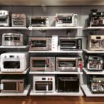 Display of assorted kitchen appliances on store shelves including toasters ovens microwaves and a coffee machine
