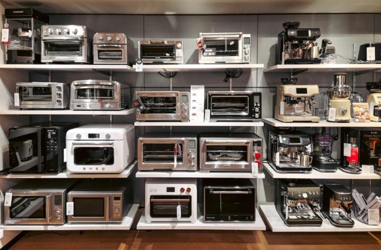 Display of assorted kitchen appliances on store shelves including toasters ovens microwaves and a coffee machine
