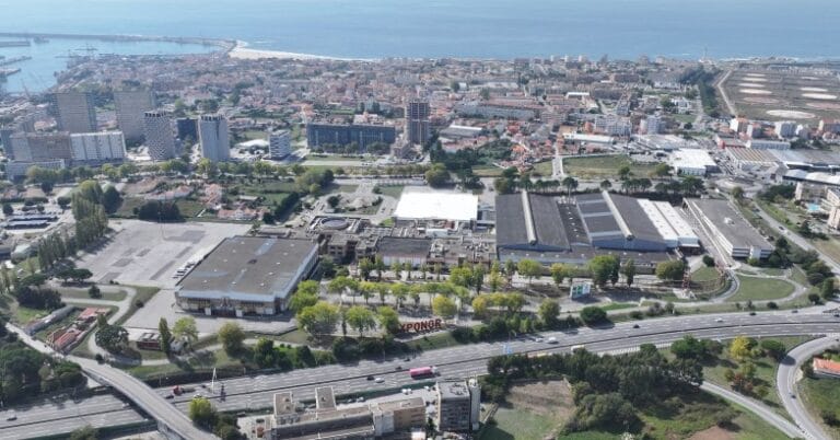 Aerial view of a coastal city with high rise buildings roads and a large industrial complex near the shoreline