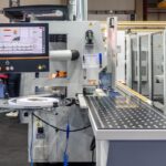 Industrial manufacturing machine with a touchscreen control panel and a conveyor on a factory floor