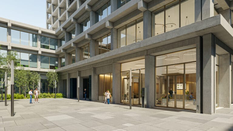 Modern concrete office building with large glass storefronts and a paved plaza with people walking and talking outside