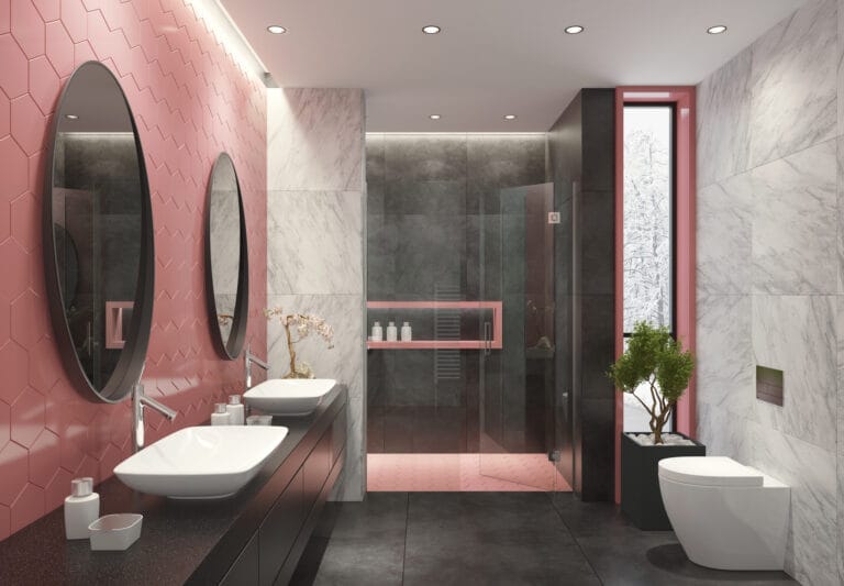 Modern bathroom with pink hex tile wall two oval mirrors above double white vessel sinks on a dark countertop