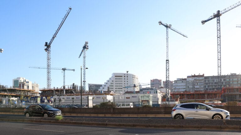 Construction site with tall cranes over under construction buildings against a clear blue sky