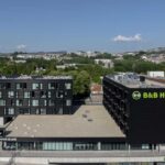 Aerial view of a black BB Hotels building with rooftop solar panels and a ground floor coworking café area