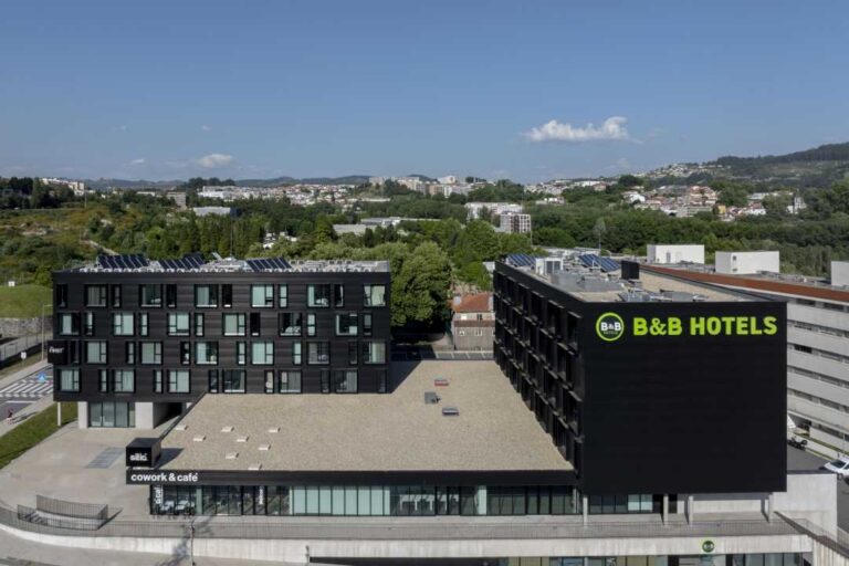 Aerial view of a black BB Hotels building with rooftop solar panels and a ground floor coworking café area