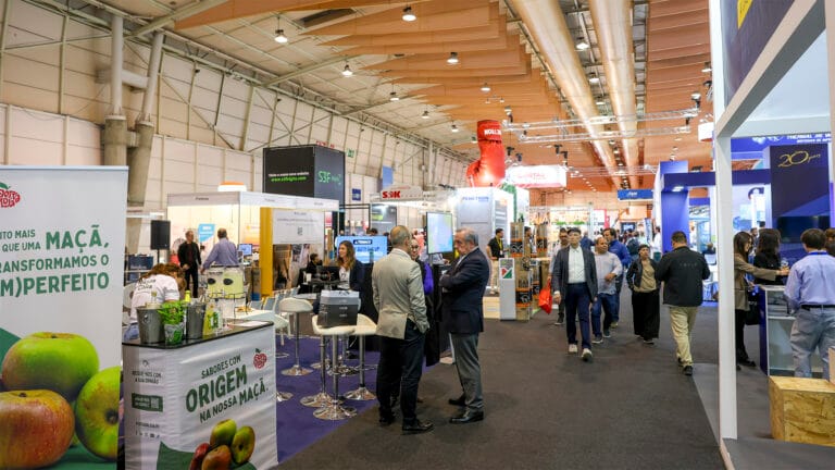 Busy trade show hall with numerous booths and attendees exploring displays and signage