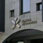 Modern stone building façade with a geometric logo and the sign CENTRO DE EMPREGO