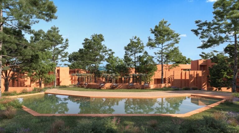 Terracotta colored modern courtyard with a rectangular pool lounge chairs and tall pine trees under a bright blue sky