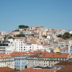 City hillside with densely packed buildings and orange roofs under a clear blue sky