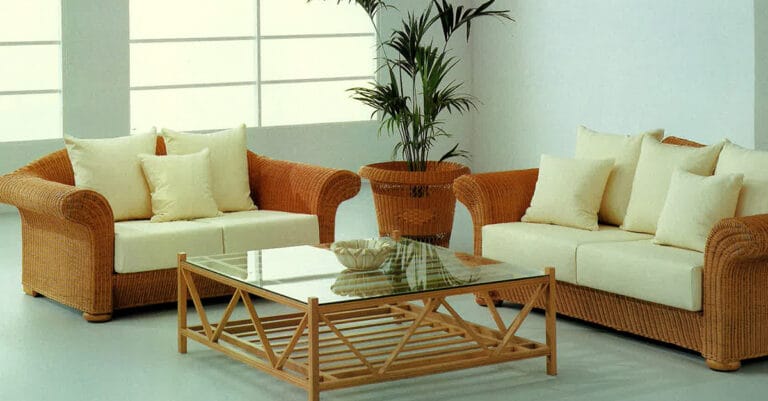 Wicker living room set with cream cushions and a glass topped coffee table in a bright minimalist space