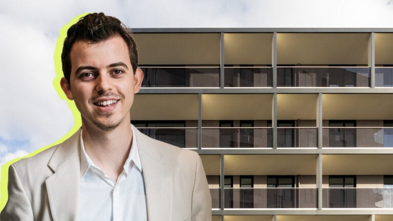 Smiling man in a light suit posing in front of a modern office building with a bright neon yellow outline behind him