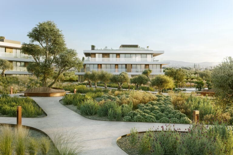 Modern multi story building with glass balconies surrounded by desert inspired landscaping and trees on a sunny day