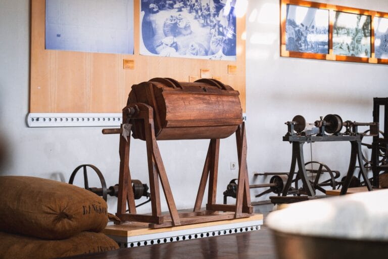 Wooden vintage milling device on a stand in a museum with blue archival photos on the wall behind