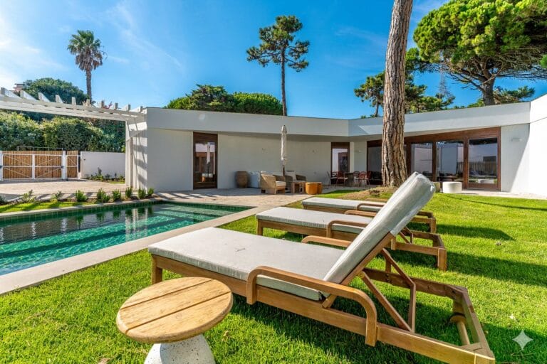 Modern backyard with a rectangular pool wooden lounge chairs and a white house with glass doors