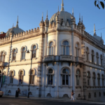 Ornate white historic building with domed turrets on a city street sunlit facade and arched windows