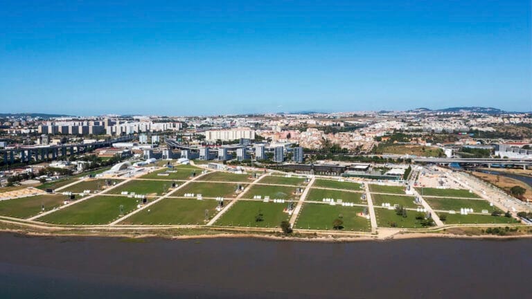 Aerial view of a city by a river with a large grid patterned park in the foreground
