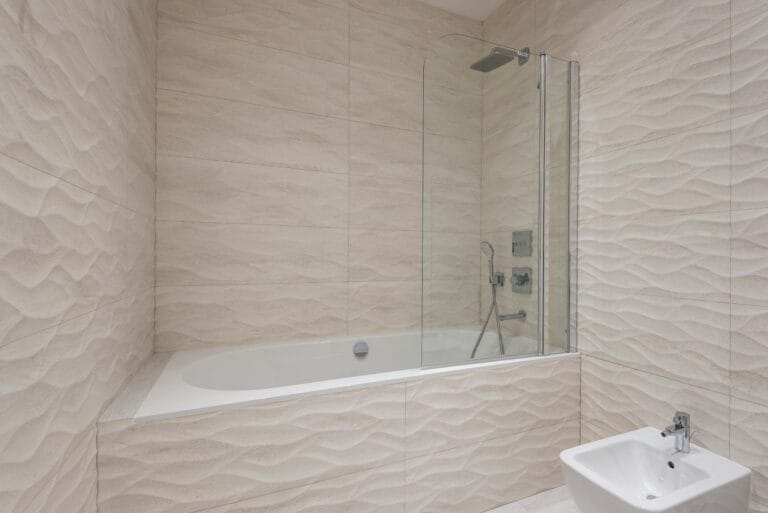 Beige tiled bathroom with a built in tub and a glass shower enclosure on the right