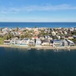 Aerial view of a coastal residential neighborhood along a calm bay with waterfront homes and docks on the waterway near the coast