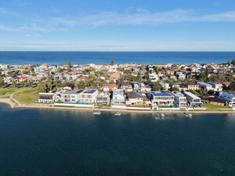 Aerial view of a coastal residential neighborhood along a calm bay with waterfront homes and docks on the waterway near the coast