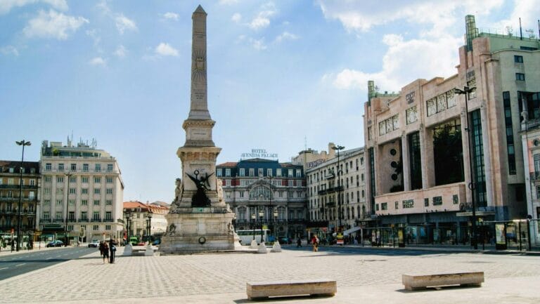 Obelisk monument in a large public square with surrounding historic buildings and pedestrians at street level