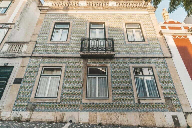 Two story house with blue green and yellow azulejo tile facade and a small central balcony