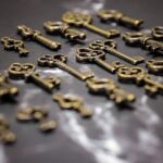 Collection of vintage brass keys scattered on a dark reflective surface