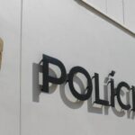 Polícia Judiciária shield badge mounted on a white wall beside the POLICIA JUDICIARIA lettering