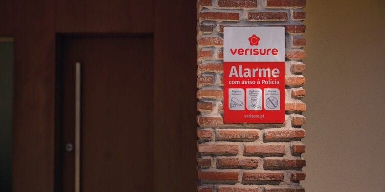 Red Verisure alarm sign mounted on a brick wall beside a doorway warning of police responsive security